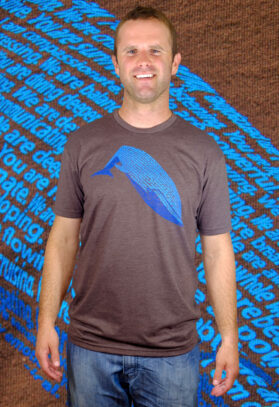 featured image of Think Possible Apparel's blue whale design screen printed on a organic cotton tee  in the color brown